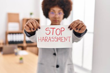 African american woman business worker holding stop harassment message banner at office