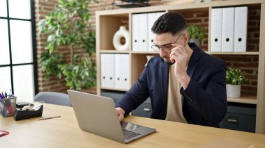 Genç Arap iş adamı ofisteki kazanan ifadesiyle laptop kullanıyor.