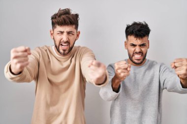 Genç homoseksüel çift, kızgın ve kızgın bir şekilde arka planda duruyor. Öfkeyle bağırırken yumruklarını kaldırıyor ve sinirleniyor. öfke ve agresif konsept. 