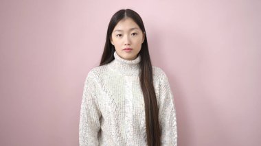 Young chinese woman standing with relaxed expression over isolated pink background