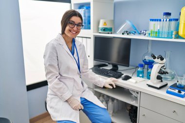Laboratuvarda çalışan, bilim adamı üniforması giyen genç İspanyol kadın.