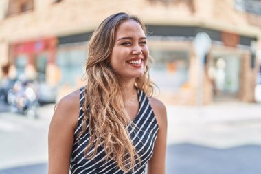 Young beautiful hispanic woman smiling confident looking to the side at street