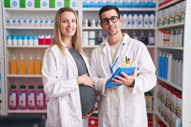 Eczanede çalışan erkek ve kadın eczacılar dokunmatik ped kullanıyorlar.