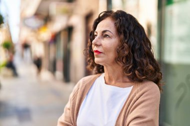 Middle age hispanic woman looking serious outdoors