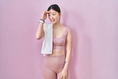 Spor kıyafetleri ve havlu giyen Çinli genç bir kadın çok mutlu ve tebessüm ediyor. arama kavramı. 