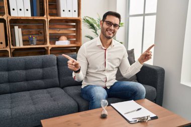 Danışma ofisinde çalışan sakallı, kendine güvenen, farklı yönleri gösteren genç İspanyol bir adam. reklam için kopyalama alanı 