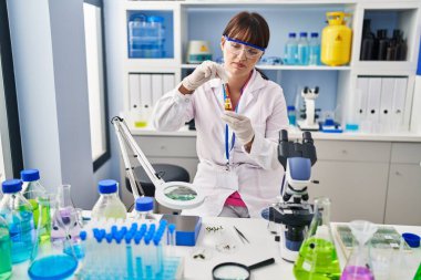 Genç ve güzel İspanyol bilim kadını eczanede bir şişe su tutuyor.