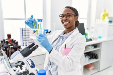 Laboratuvarda test tüpleri tutan Afrikalı Amerikalı kadın bilim adamı.