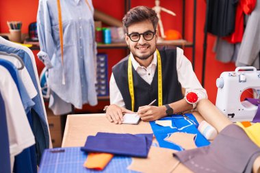 Genç İspanyol terzi atölyedeki defterde kendinden emin bir şekilde yazıyor.