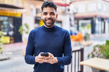 Sokakta akıllı telefon kullanan, kendine güvenen genç bir İspanyol.