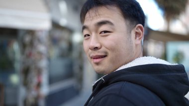 Young chinese man smiling confident standing at street