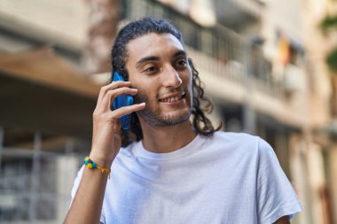 Genç İspanyol adam gülümsüyor. Kendine güveniyor. Sokakta akıllı telefondan konuşuyor.