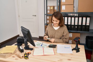 Young caucasian woman ecommerce business worker counting dollars at office