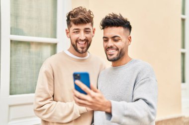 Young couple using smartphone standing together at street