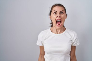 Güzel esmer kadın, izole edilmiş arka planda öfkeli ve kızgın çığlıklar içinde öfkeli ve öfkeyle bağırıyor. öfke ve agresif konsept. 