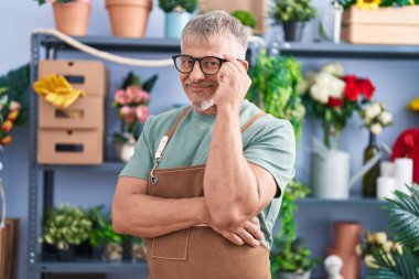 Middle age grey-haired man florist smiling confident standing with arms crossed gesture at flower shop