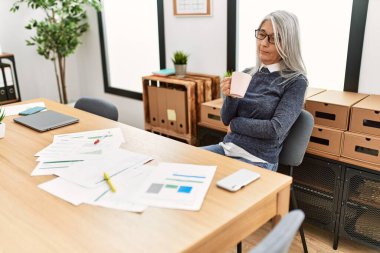 Ofiste çalışırken gülümseyen beyaz saçlı iş kadını.