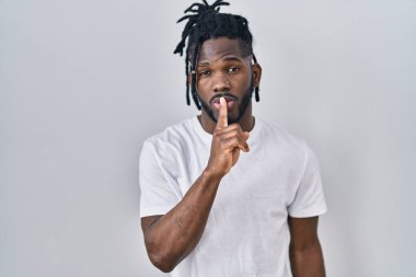 Beyaz arka planda rasta giyen Afrikalı bir adam parmakları dudaklarında sessiz olmak istiyor. sessizlik ve gizli konsept. 