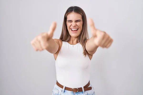 西班牙裔年轻女子站在白人背景前 赞成用手做积极的手势 微笑着竖起大拇指 为成功感到高兴 优胜手势 — 图库照片