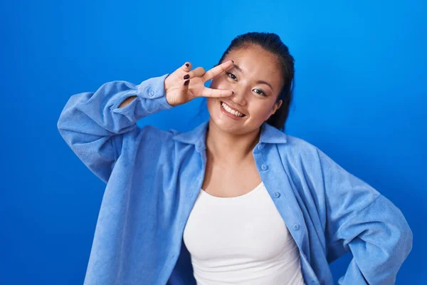 Asiatische Junge Frau Steht Vor Blauem Hintergrund Und Macht Friedenssymbol — Stockfoto