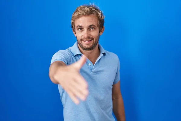 Homem Caucasiano Sobre Fundo Azul Sorrindo Amigável Oferecendo Aperto Mão — Fotografia de Stock