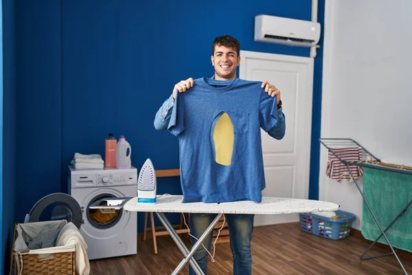 Joven Hombre Hispano Planchando Sosteniendo Camisa Hierro Quemada Lavandería Guiñando — Foto de Stock