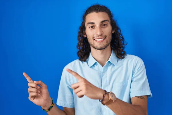 Young Hispanic Man Standing Blue Background Smiling Looking Camera Pointing — Stok fotoğraf