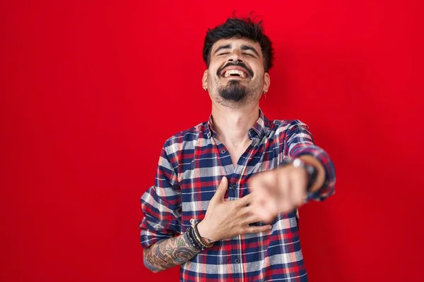 Kırmızı Arka Planda Duran Sakallı Genç Spanyol Adam Sana Gülüyor — Stok fotoğraf