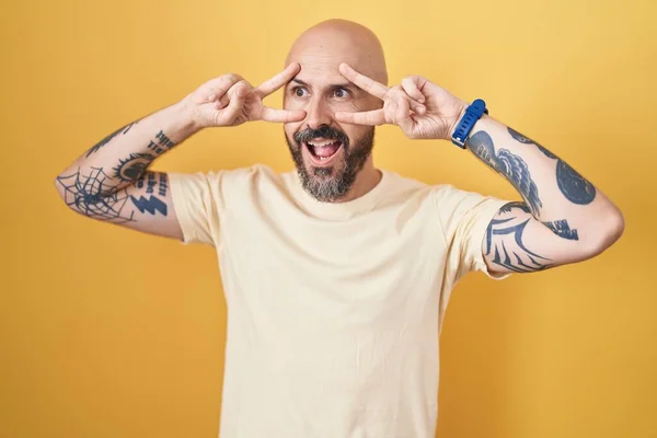 Hispánec Tetováním Stojí Nad Žlutým Pozadím Dělá Mírový Symbol Prsty — Stock fotografie