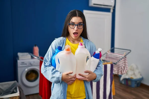 Young Hispanic Woman Holding Detergent Bottles Afraid Shocked Surprise Amazed — Stock Photo, Image