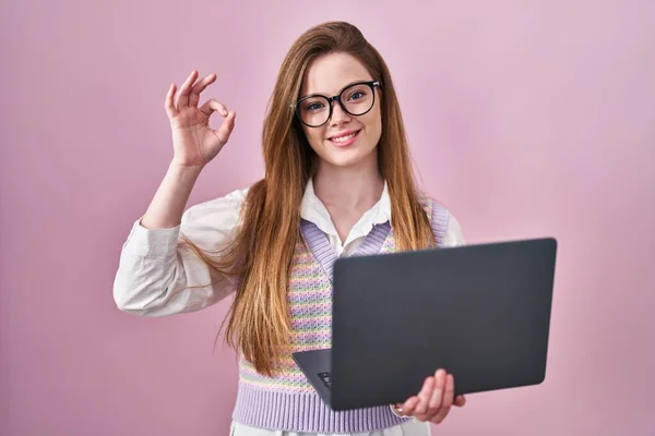 コンピュータのラップトップを使って働く若い白人女性は 手と指でOkサインをすることを肯定的に笑っています 成功した表現 — ストック写真