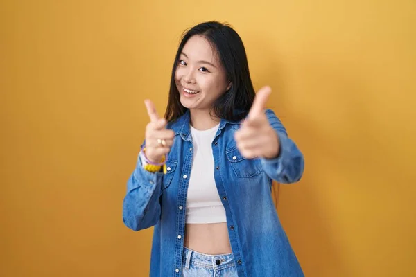 Молодая Азиатка Стоящая Жёлтом Фоне Указывая Пальцами Камеру Счастливым Смешным — стоковое фото