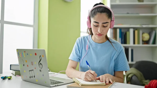 Νεαρή Όμορφη Ισπανίδα Φοιτήτρια Χρησιμοποιώντας Φορητό Υπολογιστή Και Ακουστικά Κρατώντας — Φωτογραφία Αρχείου