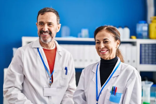 中年男性と女性科学者は自信を持って笑顔で一緒に研究室に立つ — ストック写真