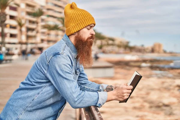 Young Redhead Man Reading Book Serious Expression Seaside — Photo