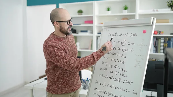 若いはげ男先生は大学の教室で磁気ボード上の数学を教える — ストック写真