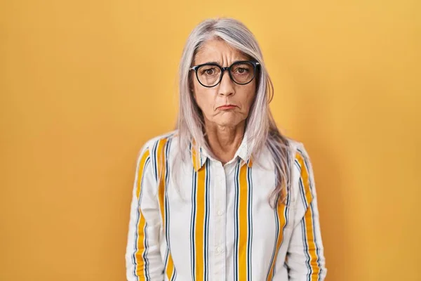 Kobieta Średnim Wieku Siwymi Włosami Stojąca Żółtym Tle Nosząca Okulary — Zdjęcie stockowe