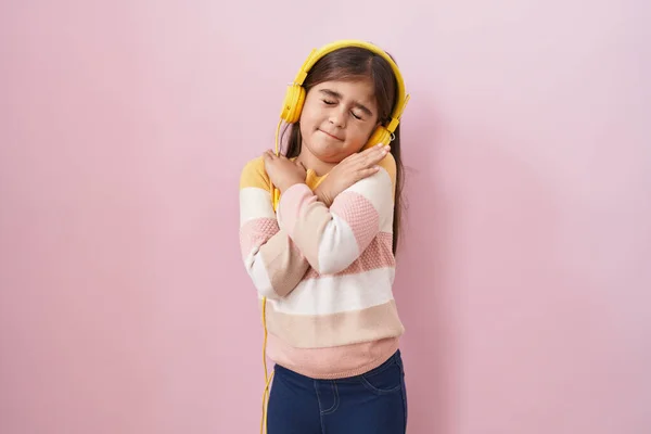ヘッドフォンを使用して音楽を聞いている小さなヒスパニック系の女の子は 自分自身幸せと肯定的な抱擁 自信を笑顔 自己愛と自己ケア — ストック写真