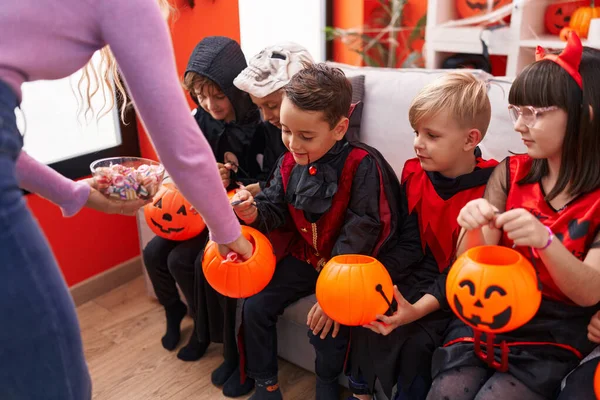 ハロウィンの衣装を着ている子供たちのグループは 自宅でカボチャのバスケットでキャンディーを受け取ります — ストック写真