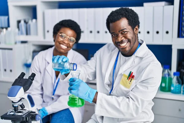 実験室で液体を測定するアフリカ系アメリカ人男性と女性科学者 — ストック写真