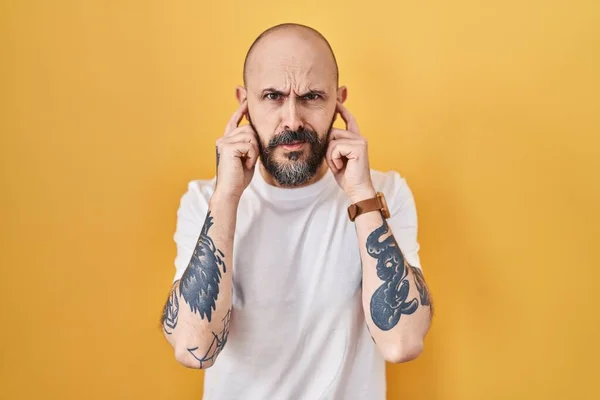 Young Hispanic Man Tattoos Standing Yellow Background Covering Ears Fingers —  Fotos de Stock