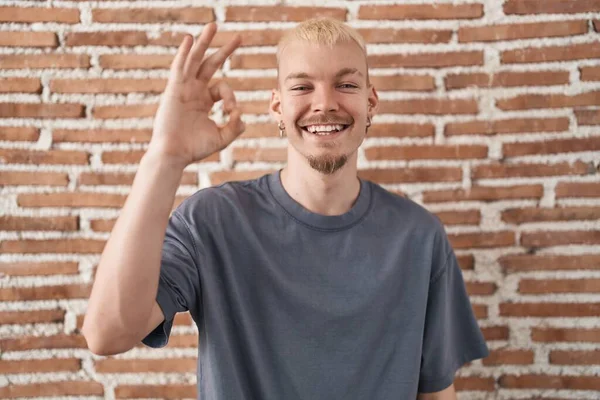 Tuğla Duvarın Üzerinde Duran Beyaz Bir Genç Olumlu Gülümsüyor Parmaklarıyla — Stok fotoğraf