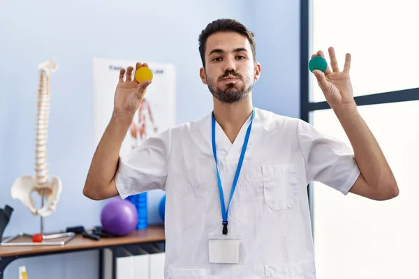 Young Hispanic Physiotherapist Man Holding Strength Balls Train Hand Muscles — Stock Photo, Image