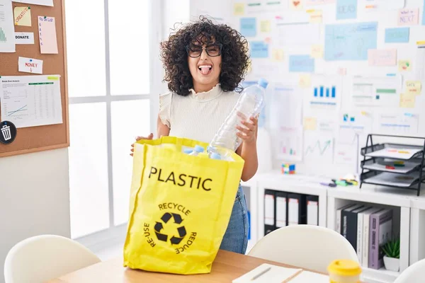 若いです中東女性保持リサイクルバッグとともにプラスチックボトルでオフィススティック舌アウト幸せな面白い式 — ストック写真
