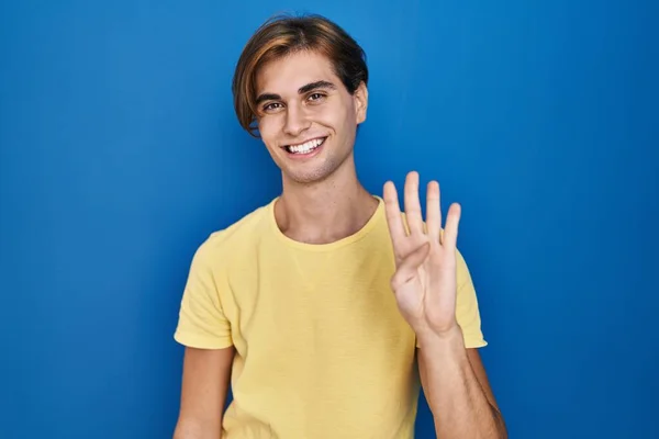 Mavi Arka Planda Duran Genç Adam Kendinden Emin Mutlu Gülümserken — Stok fotoğraf