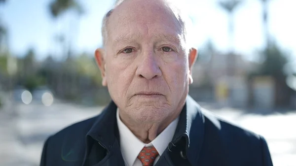 stock image senior standing with serious expression at street