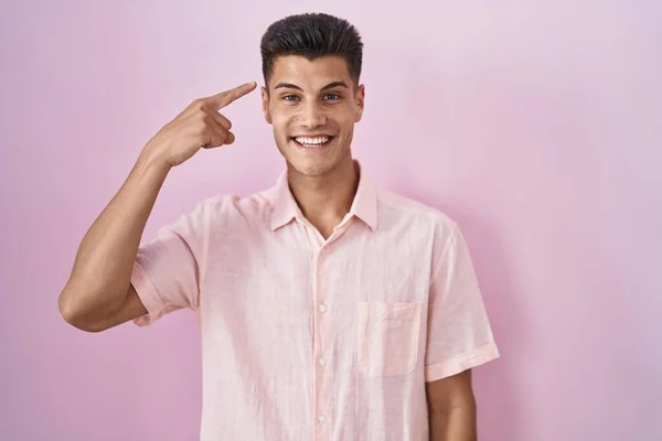 Молодий Іспаномовний Чоловік Стоїть Над Рожевим Тлом Посміхаючись Вказуючи Голову — стокове фото