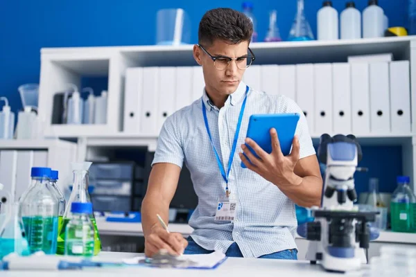 Young Hispanic Man Scientist Using Laptop Writing Clipboard Laboratory — ストック写真