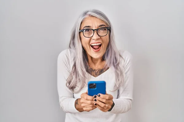 スマートフォンの入力メッセージを使用して白髪の中年の女性は笑顔と大声で笑いますので面白いクレイジー冗談 — ストック写真