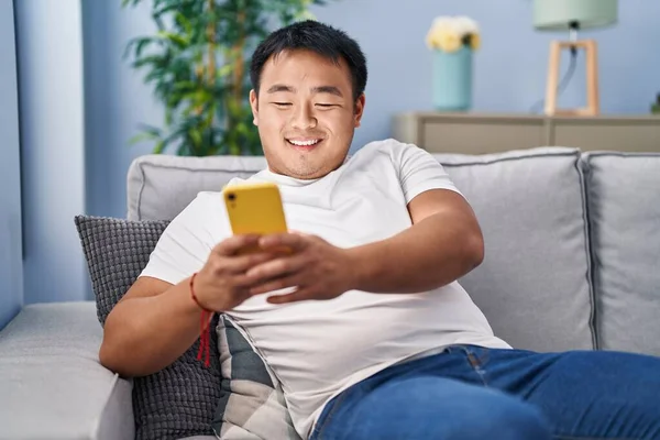 Hombre Chino Joven Usando Teléfono Inteligente Sentado Sofá Casa —  Fotos de Stock